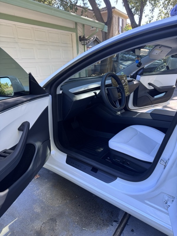 Tesla Model 3 with the door open after a detail, white leather seats clean